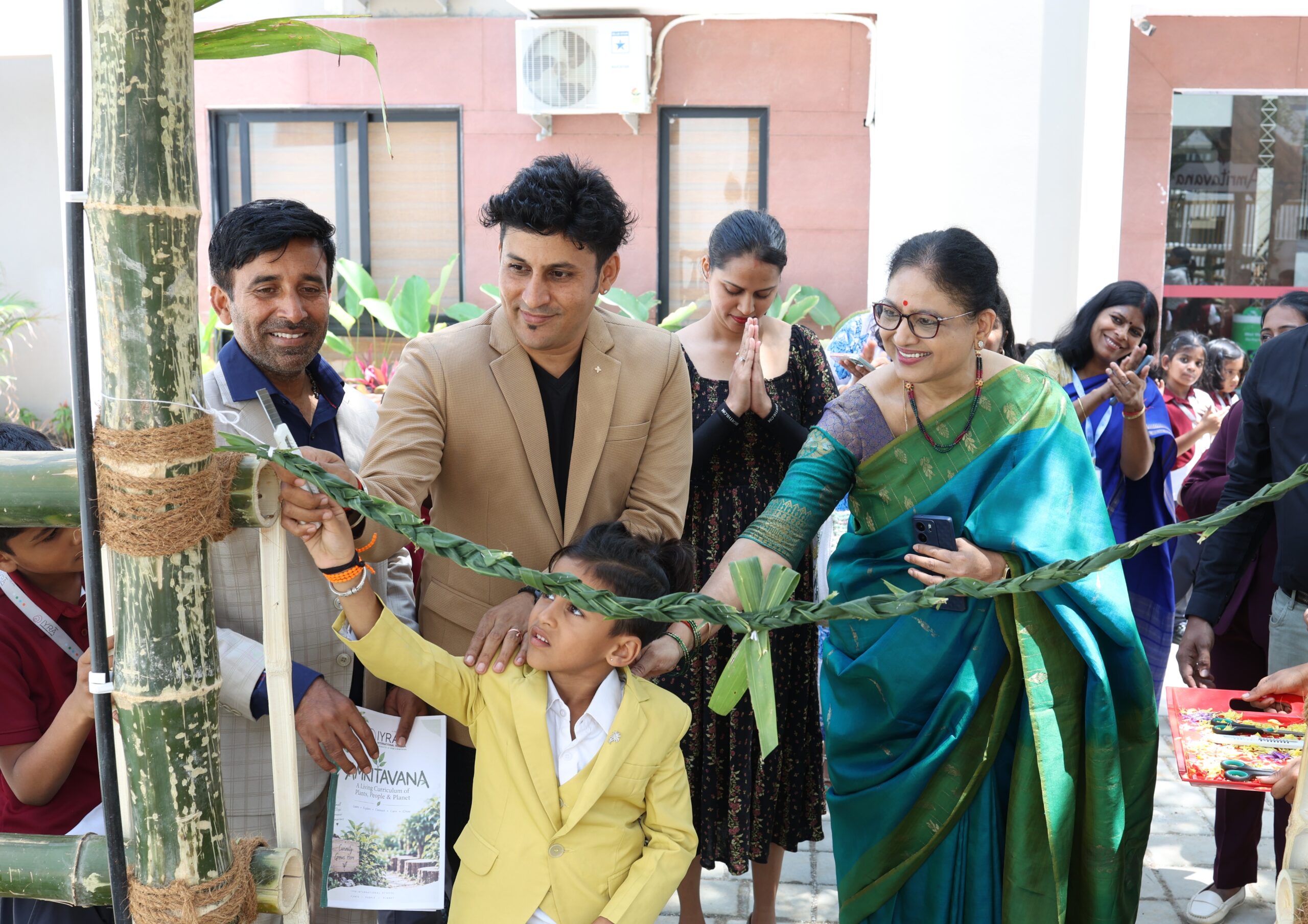 A child and adults cut a braided green ribbon at the bamboo entrance to Amritavana during the garden opening ceremony.